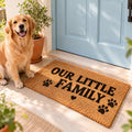 Coir doormat reading "OUR LITTLE FAMILY" at a pale blue front door with a golden retriever